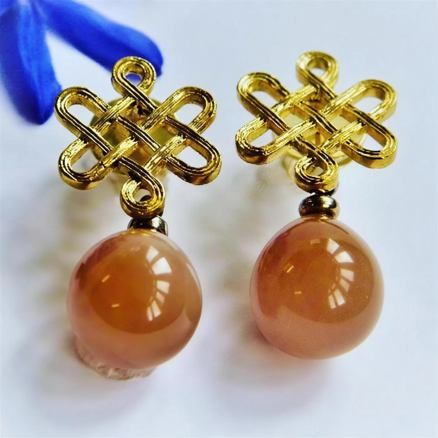 Goldene Ohrstecker mit Knotenornament und apricotfarbenen Steinkugeln