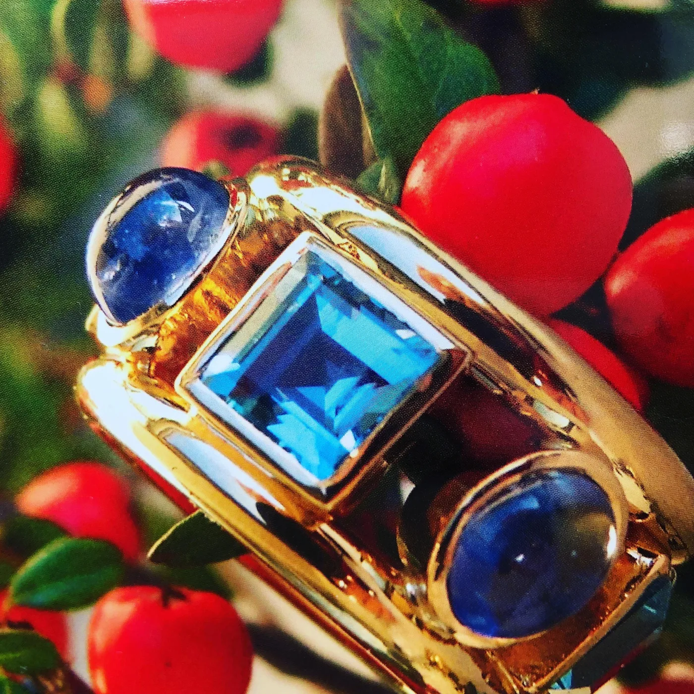 Gelbgoldring mit blauem Stein im Carré-Schliff und zwei blauen Cabochons